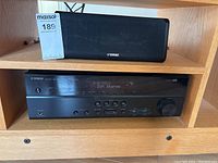 Receiver unit on wooden shelf with center speaker above