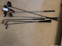 Full view of all golf clubs including drivers and irons laid on carpet