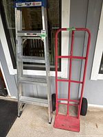 Photo showing ladder and hand cart side by side against the exterior wall.