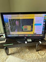 Front view of 60-inch LG plasma TV powered on displaying a video and computer desktop.