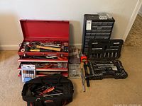 Full view of red Craftsman toolbox, black tool bag, socket cases, parts organizer and accessories on floor