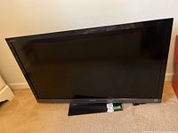 Full view of Sony 46-inch flat screen TV with base stand sitting on carpeted floor.