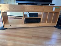 Front view showing the full TV and stereo stand with three drawers, open shelf, and vertical album slots.