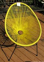 Front view of yellow Acapulco chair showing woven seat and black metal legs