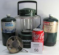Photo shows Rayovac green camping lantern, two one-pound propane cylinders (River Trail and Coleman), single element camping stove, and a Coca-Cola can for scale.