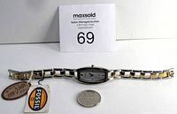 Front view of the Fossil f2 ladies watch showing the rectangular face, two-tone metal band, and attached original tags, placed next to a quarter for scale.