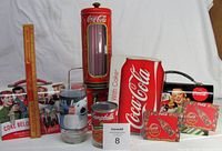 Full lot overview showing all nine Coca Cola related items arranged together including lunch boxes, straw holder with straws, cookbook, ruler, glass, and magnets.