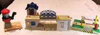 Three large Thomas the Tank Engine track features displayed: a drawbridge in center with blue roofed house and blue lattice bridge, a railroad crossing with signal and gates, and a water tower with red conical roof on beige base