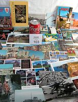 Photo showing assortment of postcards featuring various landmarks and locations from Europe and Asia, including color and black and white images, plus souvenir booklets.