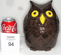 Brown ceramic owl-shaped cookie jar with glossy finish, large yellow eyes, detailed feathers, 8 inches tall reference against soda can.