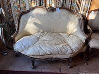 Front view of antique sofa showing solid wood carved frame and worn upholstery with stained and torn fabric.