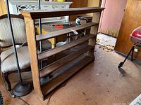 Front and side view of the wooden farmhouse shelf unit showing the three shelves and decorative molding along the top and side panels.