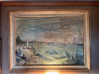 Framed landscape painting showing coastal scene with sailboats and figures along beach.