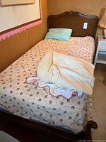 Full view of the single bed frame made of solid wood with floral bedding and pillows