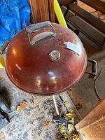 Top-down view of red Weber kettle grill with lid closed showing metal handle and thermometer.