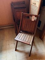 Six wooden folding chairs, one in front showing slatted seat and back, one chair visibly broken.