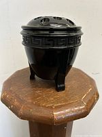 Side view of the amethyst glass pedestal vase showing the Greek key design around the rim and three-legged pedestal base.