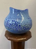 Front angle view of blue cratered art glass vase with texture and shine visible