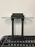 Front perspective showing the overall lamp structure with matte black base and glass top