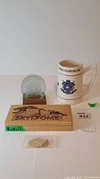 Photo of all memorabilia items together: wooden SkyDome pen box, glass coasters with wooden stand, ceramic stein, SkyDome keychain.