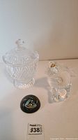 Photo of all three items: Irish-style crystal candy dish with lid, glass fish sculpture holding a fishing fly, and black glass paperweight with fishing fly image