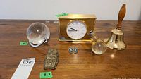 Lot contents showing Tiffany & Co. brass clock, crystal globe, brass owl clip, glass light bulb ornament, and brass bell