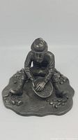 Front close-up showing prospector seated panning for gold, detailed pewter casting and textured rocky base
