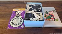 Box of mixed vintage 35mm slides and unopened Wishbone Viewmaster package with a circular viewer featuring a dog image on the cover.