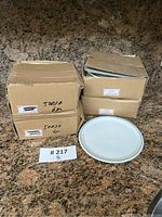 Stacked cardboard boxes labeled with Canadian Airlines and pattern number 50030, with one white ceramic plate on display.