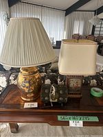 Two Asian style lamps and one decorative box on a wooden table in a living room, showing the whole lot.