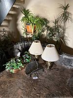 Overall view showing two lamps, plant stand with wicker planter, live spider plant, fireplace tools, faux flowers in copper planter, coal scuttle