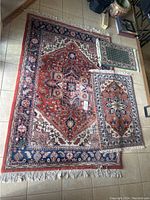 Three hand knotted rugs arranged on tiled floor, showing sizes and general patterns