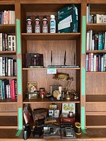 Wooden shelving unit with all items: dusters, envelopes, desk accessories, brass lamp, clock and push pin jar