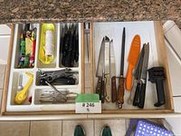 Opened kitchen drawer with organized utensils and tools visible on granite counter top