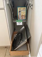 Photo showing the open kitchen drawer containing two metal baking sheets and a black cooling rack, with the Marcato Cookie Press box standing on the counter above.