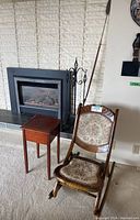 View of the folding rocking chair and wooden side table together in front of fireplace.