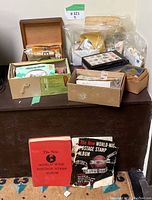 Large collection of stamp albums and boxes with loose stamps and related materials on a table.