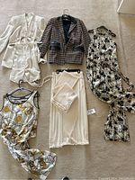Lot of three vintage 1990s matching sets including blazers, tops, rompers, and skirt laid out on a beige carpet.