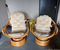 Pair of vintage bamboo armchairs positioned side-by-side with beige tufted cushions in a garage environment.
