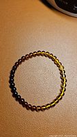 Top view of the Baltic amber bracelet laid flat showing the round beads in gradient amber colors from dark brown to honey yellow.