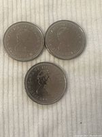 Obverse side of three Canadian dollar coins showing Queen Elizabeth II portrait with inscriptions.