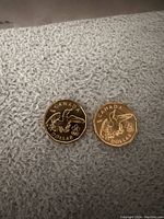 Photo of the obverse sides showing the Olympic commemorative coin and standard coin with bird and Olympic rings design.