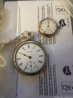 Front view of Waltham pocket watch face showing white dial with Roman numerals and subsidiary seconds dial