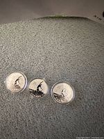 Front sides of three silver coins showing a figure in motion and denominations.