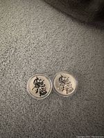 Two 2016 Canadian $20 silver coins showing the reverse sides with a hockey player design, placed on a grey fabric.