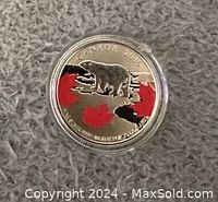 Close-up photo of the coin's side depicting a polar bear and red maple leaves, encased in a protective plastic holder.