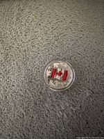 Photo of the obverse side showing the colored Canadian flag and maple leaf design on a silver coin.