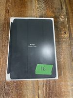 Front image of the unopened black Apple iPad Smart Cover box with white Apple logo and text.