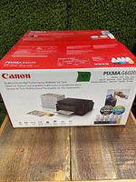 Front of sealed Canon Pixma G6020 box showing printer image, ink bottles and box graphics