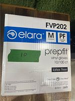 Photo of one box labelled Elara FVP202 medium powder-free vinyl gloves with details about quantity and usage.